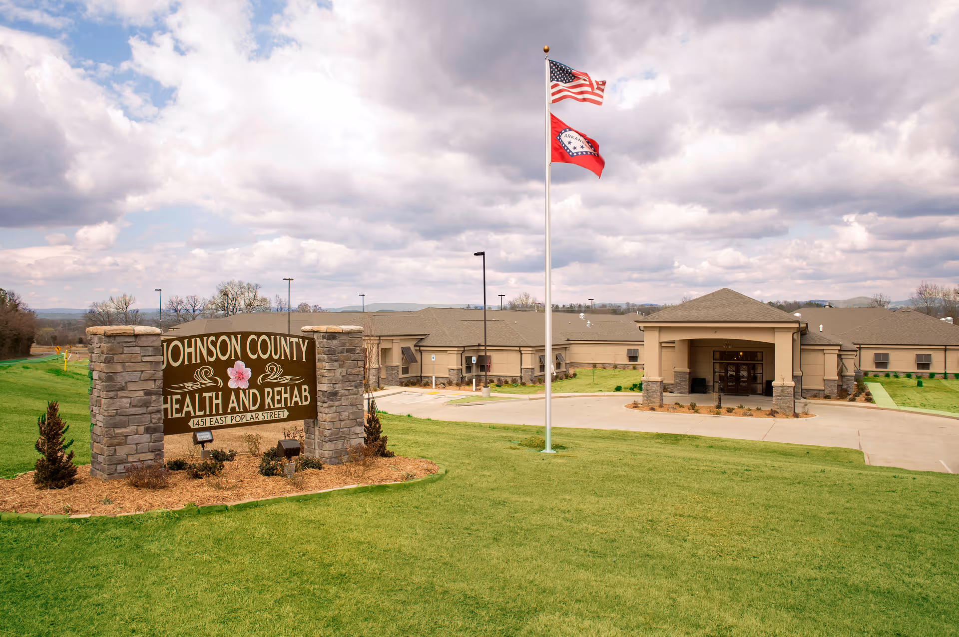 Exterior view of Johnson County Health and Rehab front with sign, flagpole, and entrance.