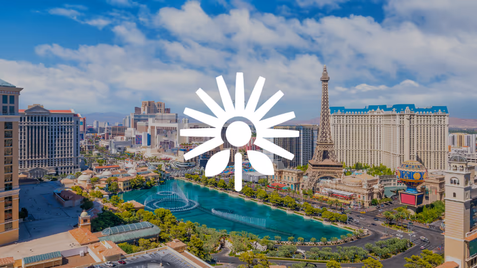 Wide cityscape of Las Vegas with a river, fountains, and iconic hotels.