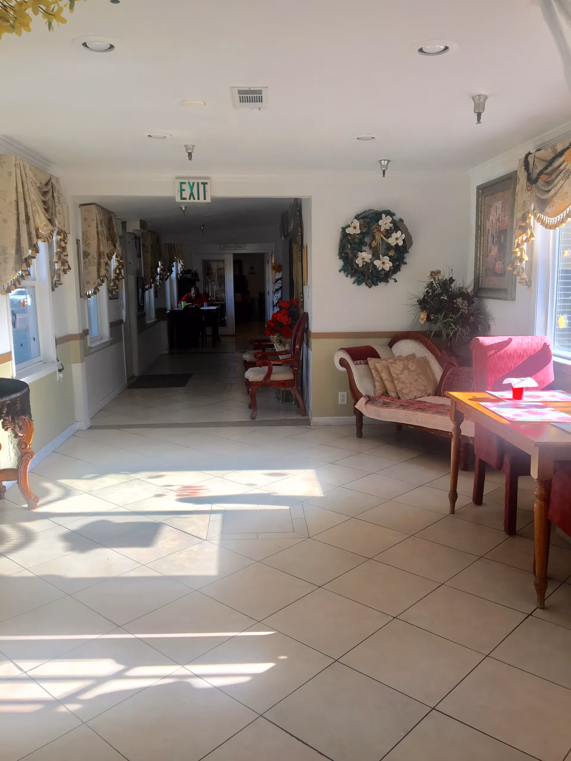 Bright interior with tiled floor, seating area, and exit sign above the hallway.
