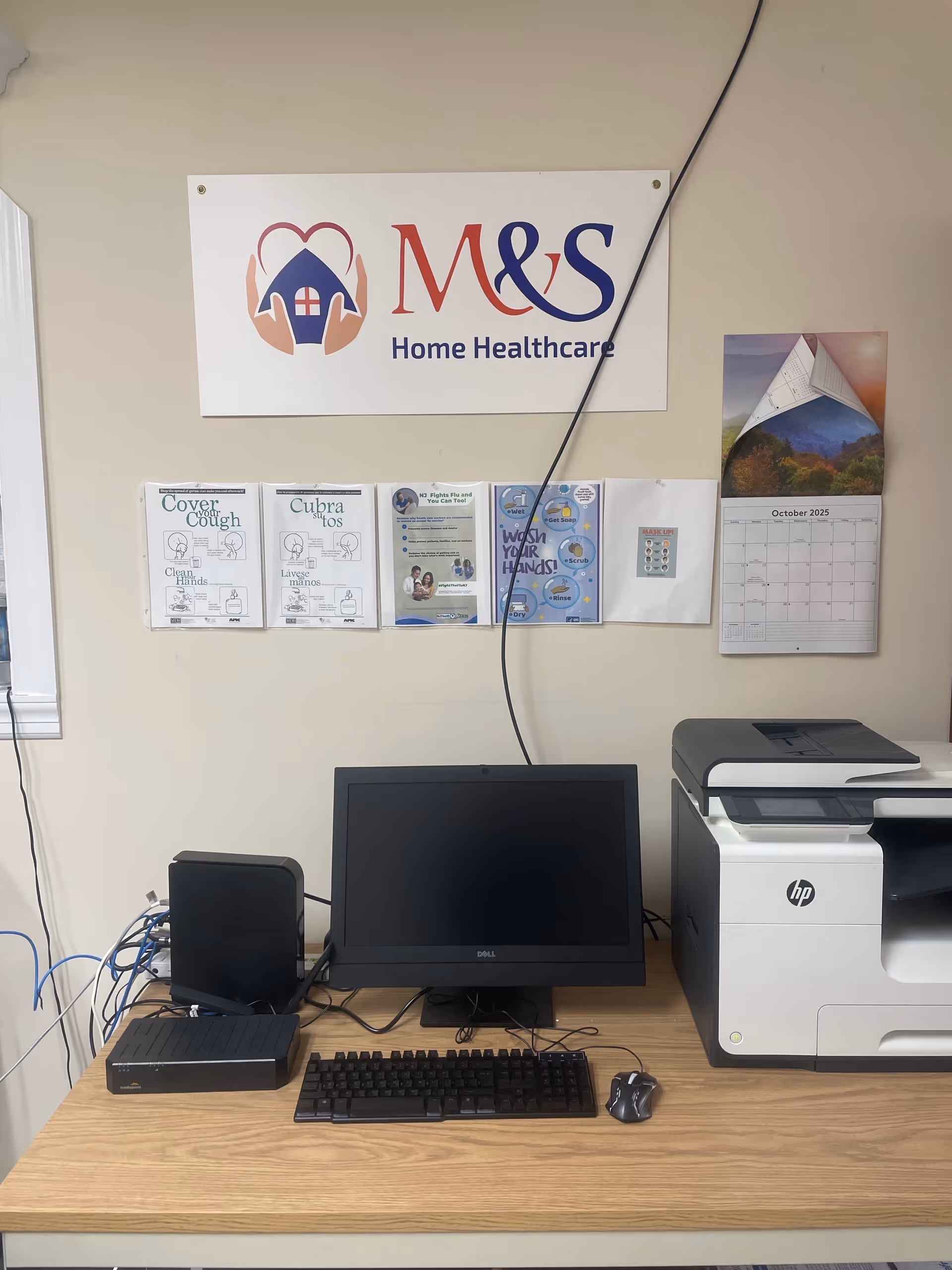 Office desk setup with computer, printer, and wall sign reading M&S Home Healthcare
