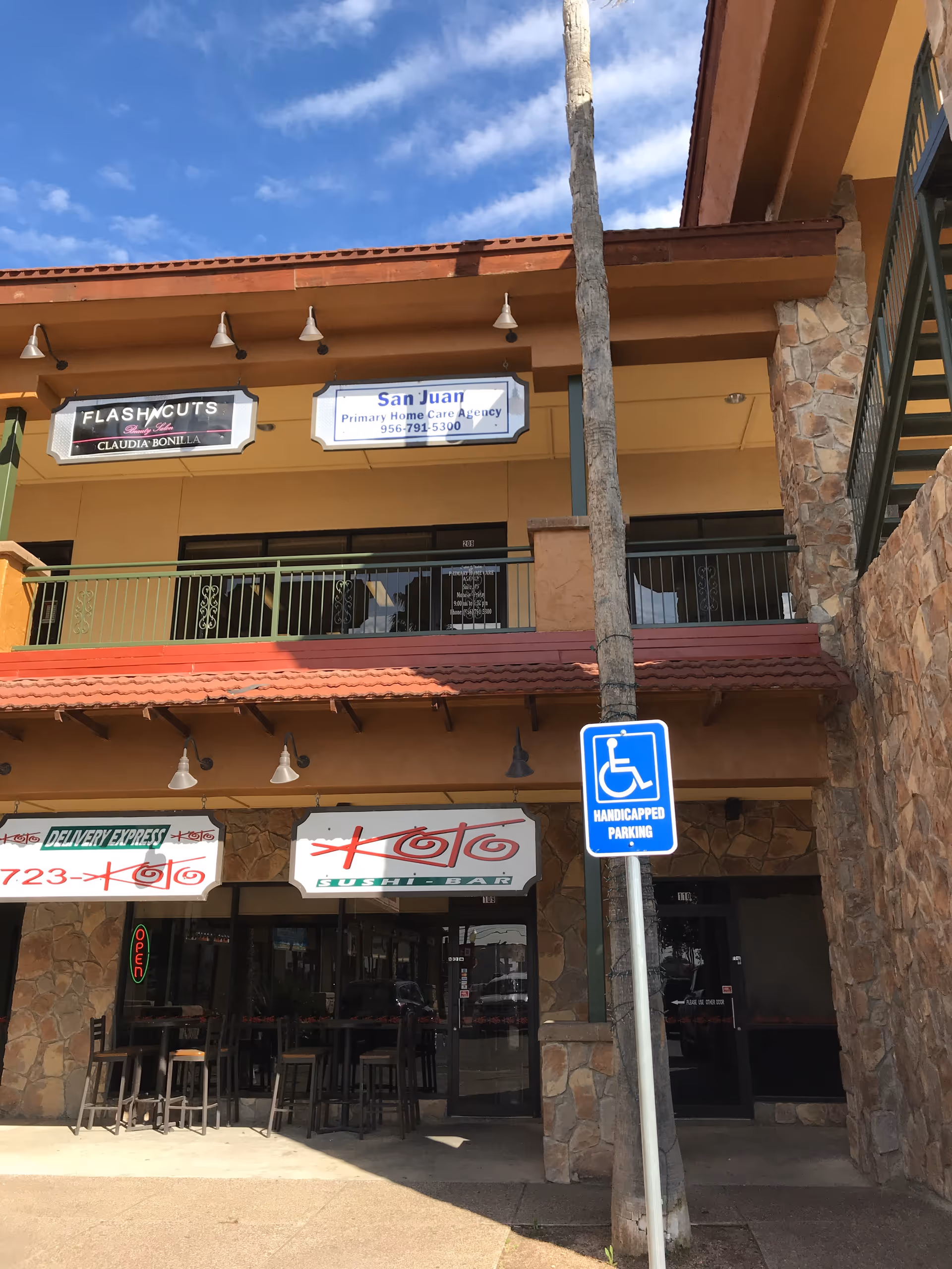 Two-story shopping center exterior with San Juan Primary Home Care Agency sign and handicapped parking sign