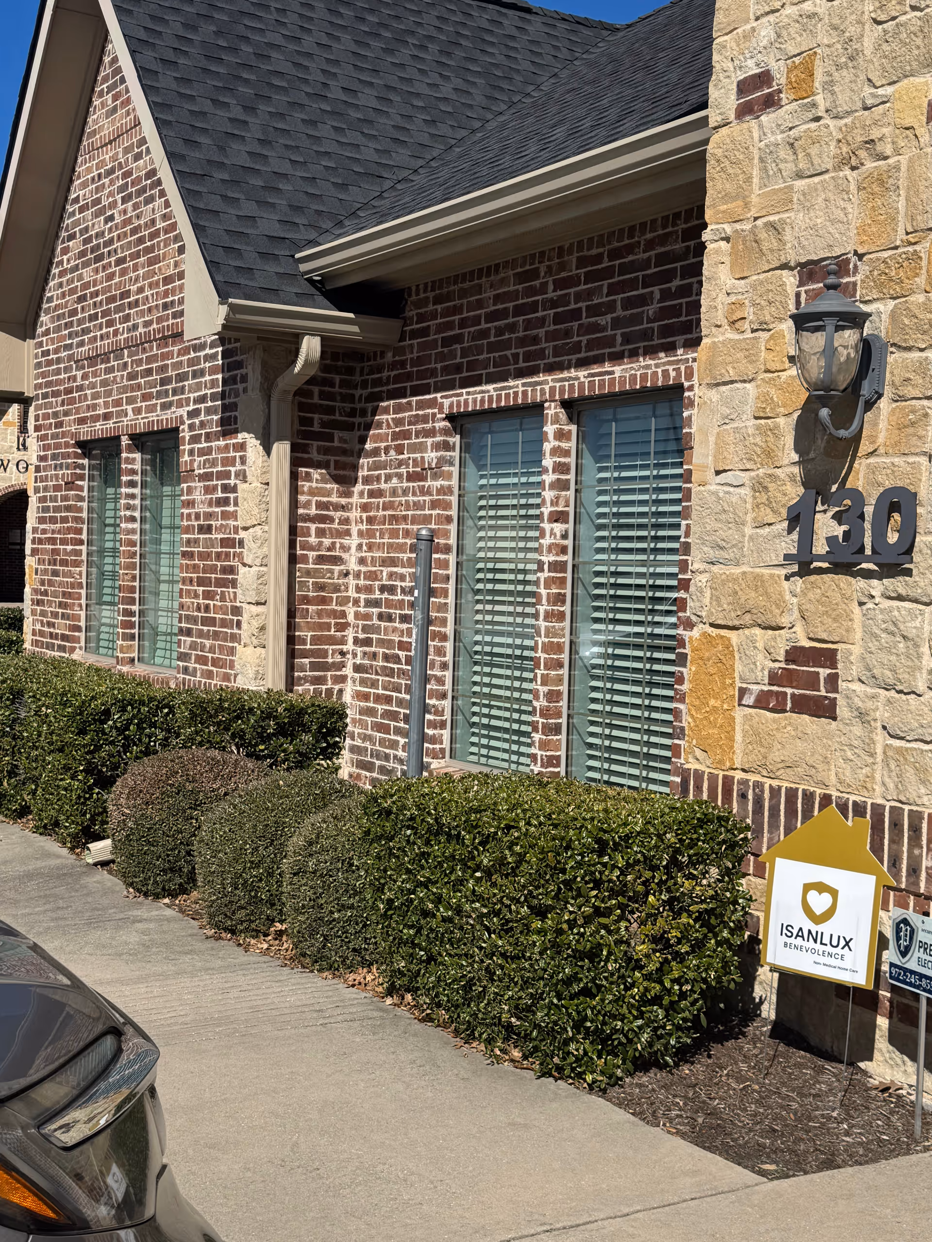 Exterior view of a brick senior living facility with stone accents and an ISANLUX Benevolence sign.