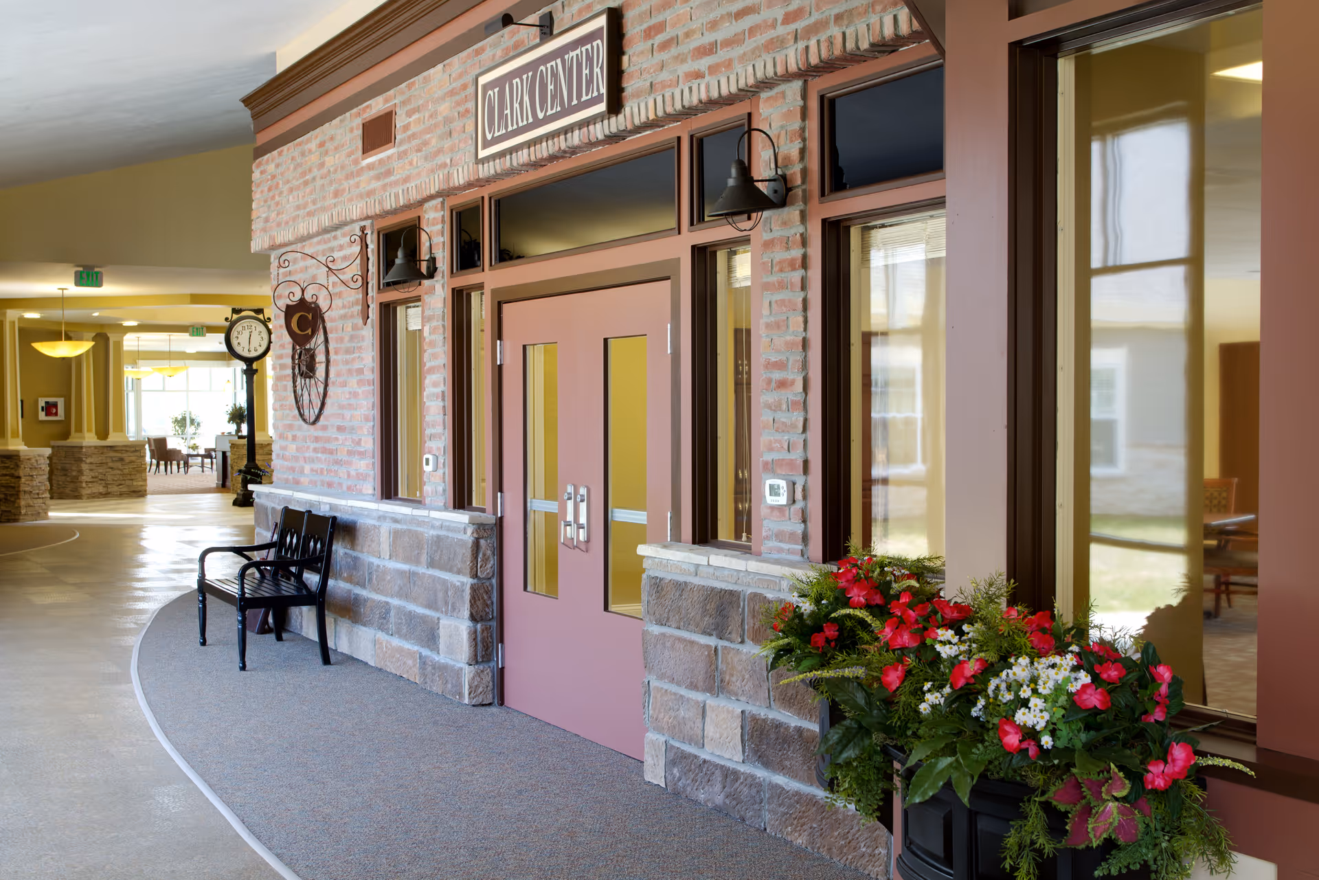 Brick-clad entrance with bench, flowers, and glass doors at Randall Residence of Tipp City.