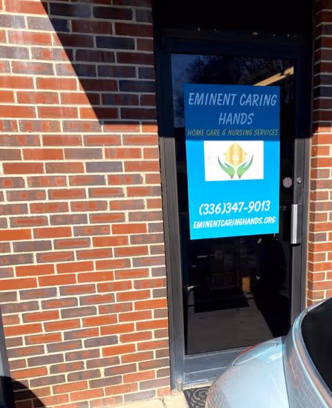 Brick exterior with a glass door displaying Eminent Caring Hands sign and blue logo.