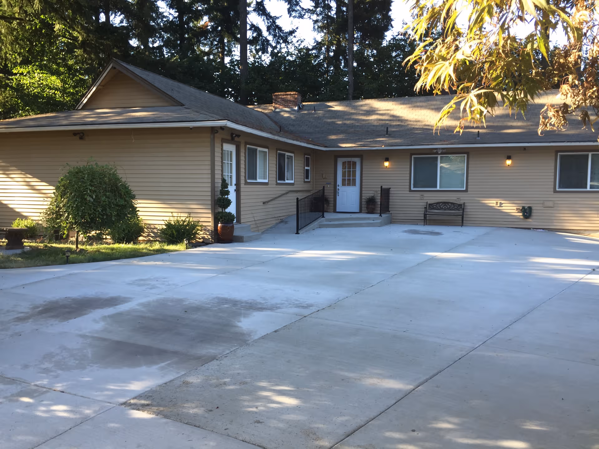 Front view of a beige, single-story senior living facility with a wide concrete driveway.