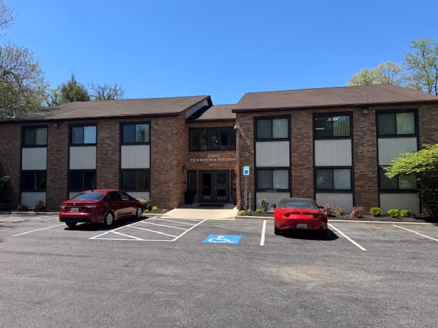 Brick exterior of a senior living building with a parking lot and handicap space in front.