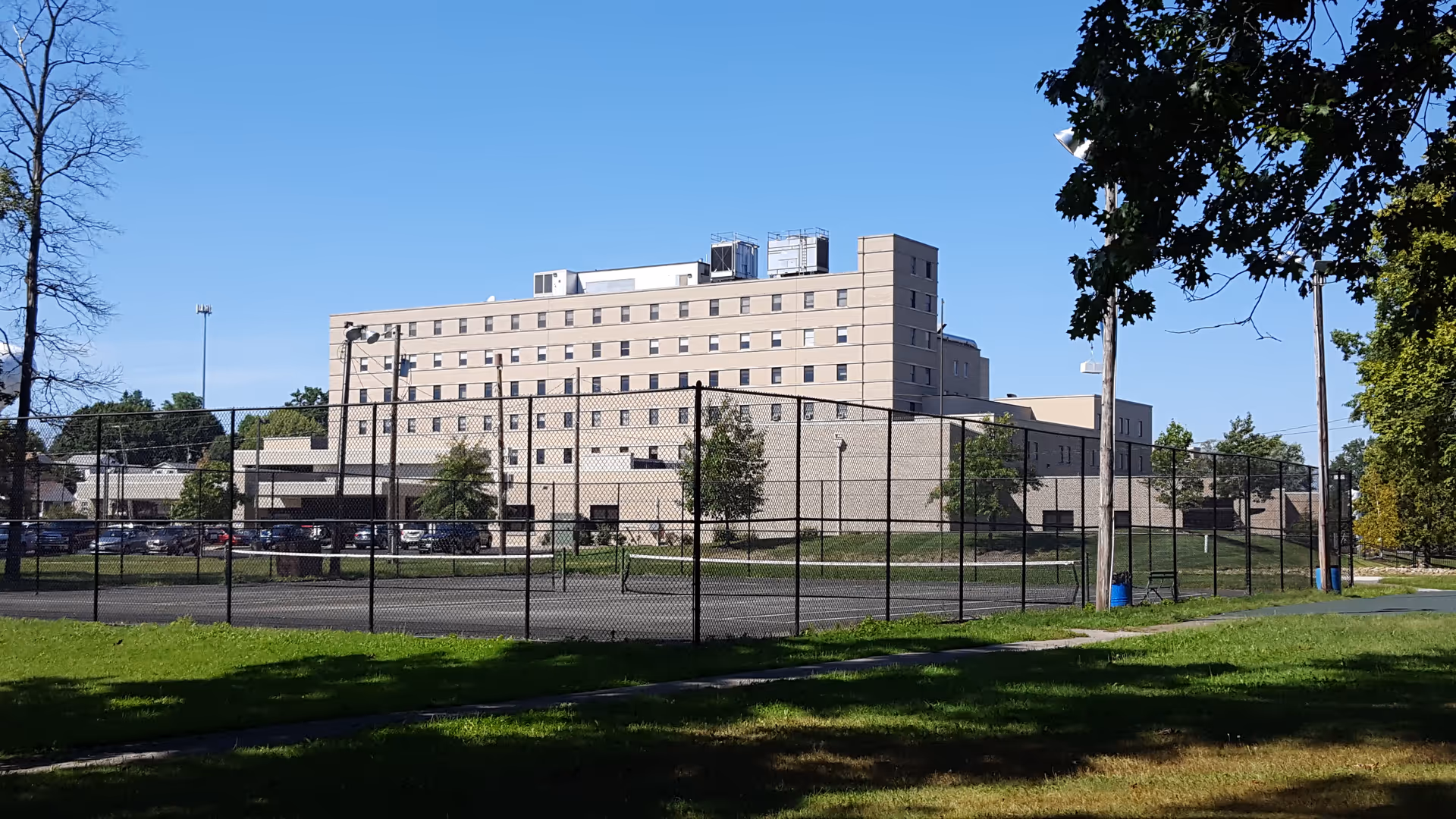 Saber Skilled Nursing Unit at Barberton building behind a chain-link fence enclosing an outdoor court.