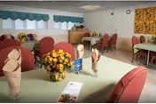 Milford Health Care Center dining room with red chairs and floral centerpiece.