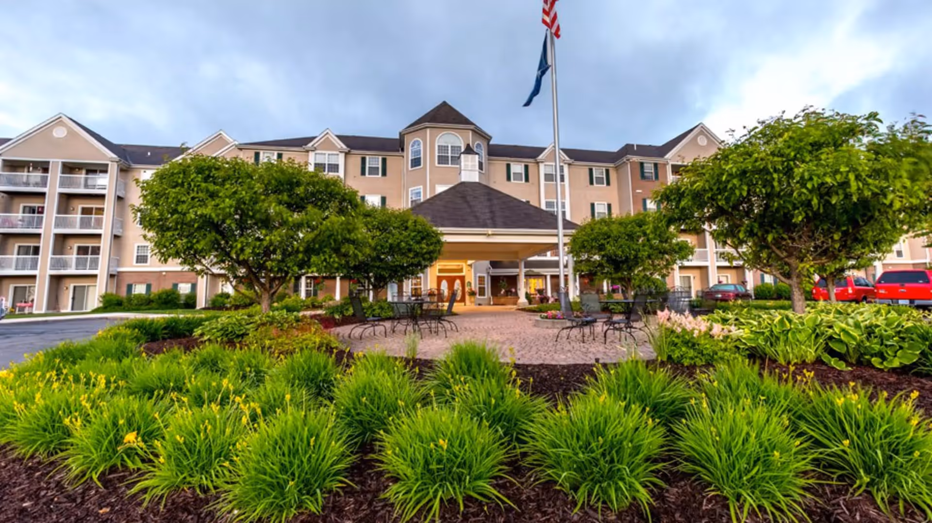 Front view of Independence Village of Petoskey showing entrance, flagpole, and landscaped courtyard