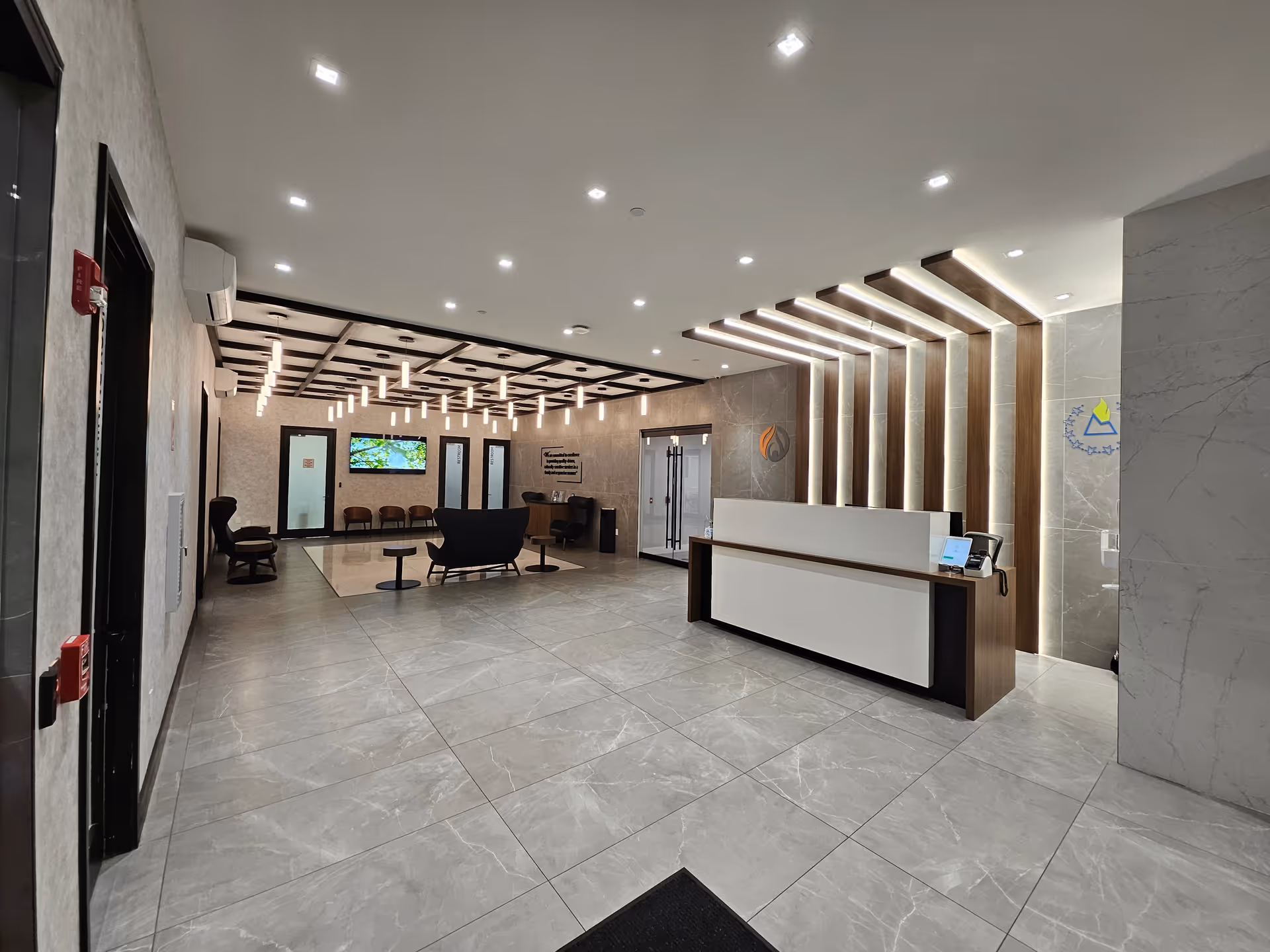 Modern senior living lobby with reception desk, marble floors, and lounge seating under contemporary lighting.