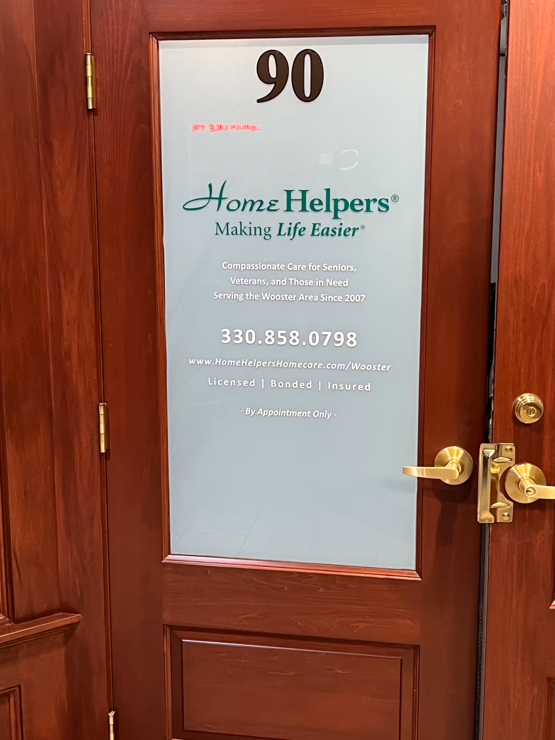 A wooden door with frosted glass displaying Home Helpers logo and contact information, door 90.