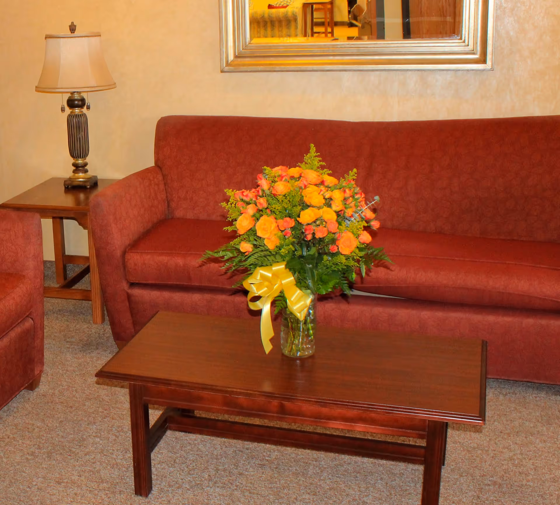 Lounge area at SunQuest Village of Yuma with red sofa and bouquet.