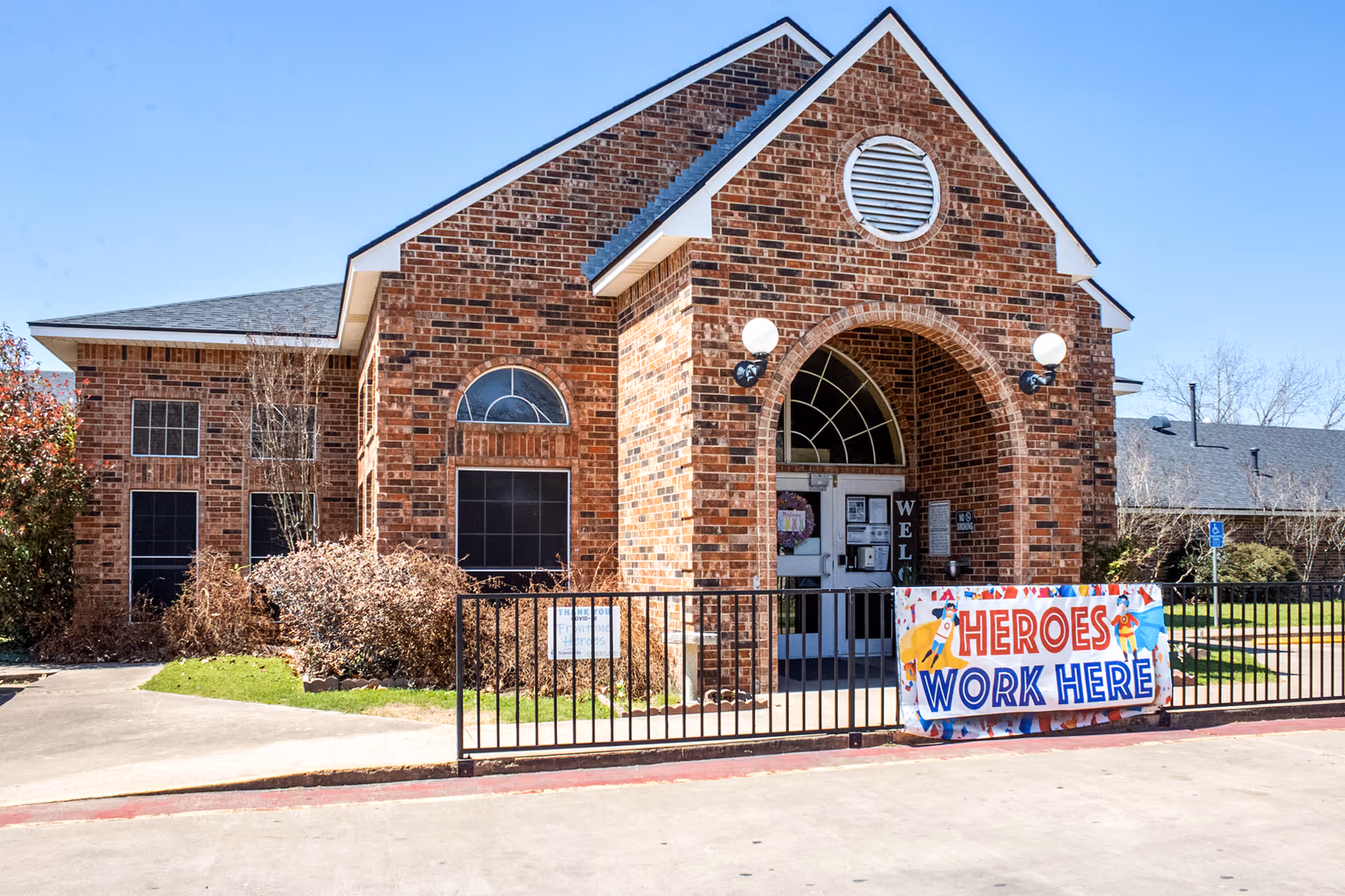 Brick senior care building with arched entrance and banner reading Heroes Work Here.