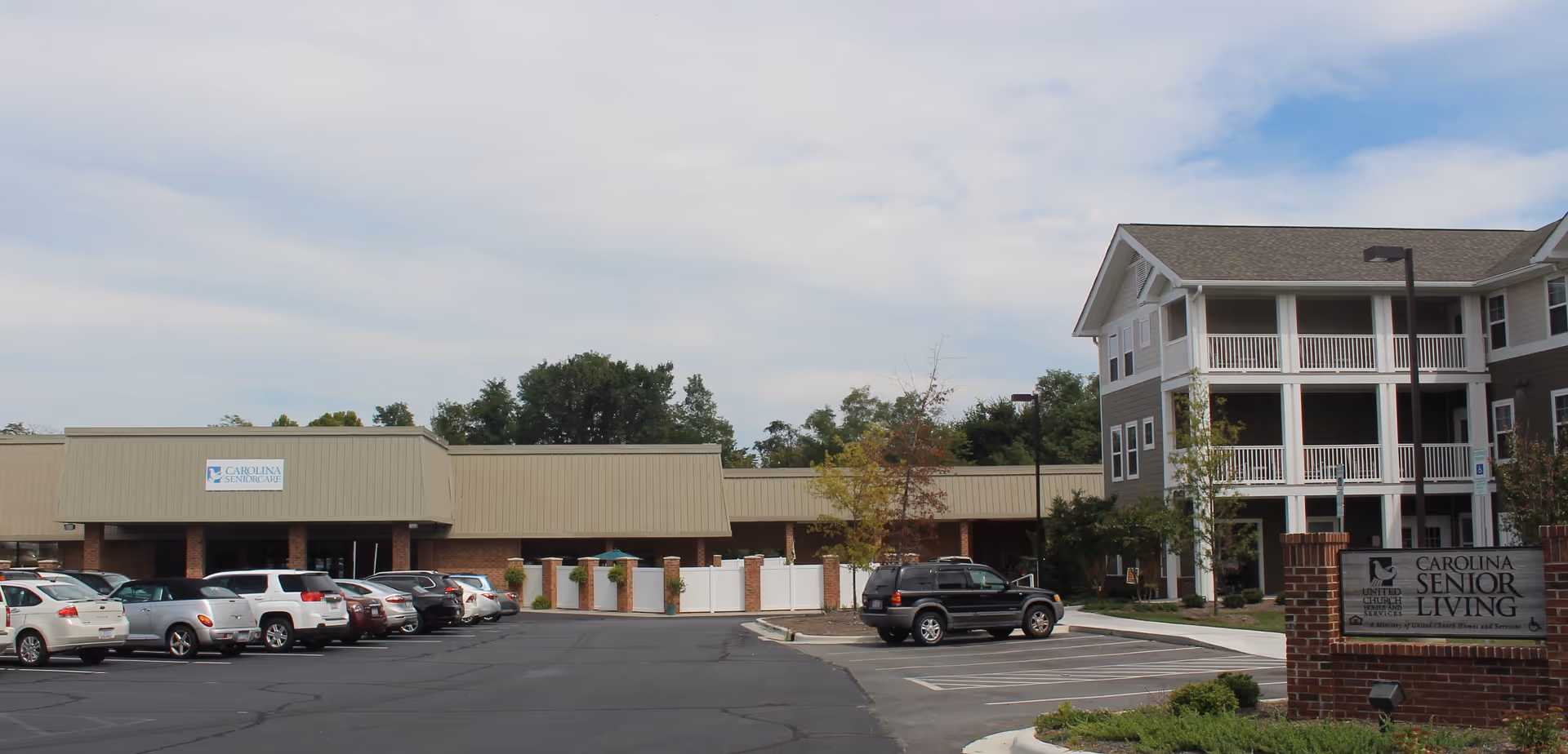 Exterior view of a senior care facility with a parking lot and multi-story building.