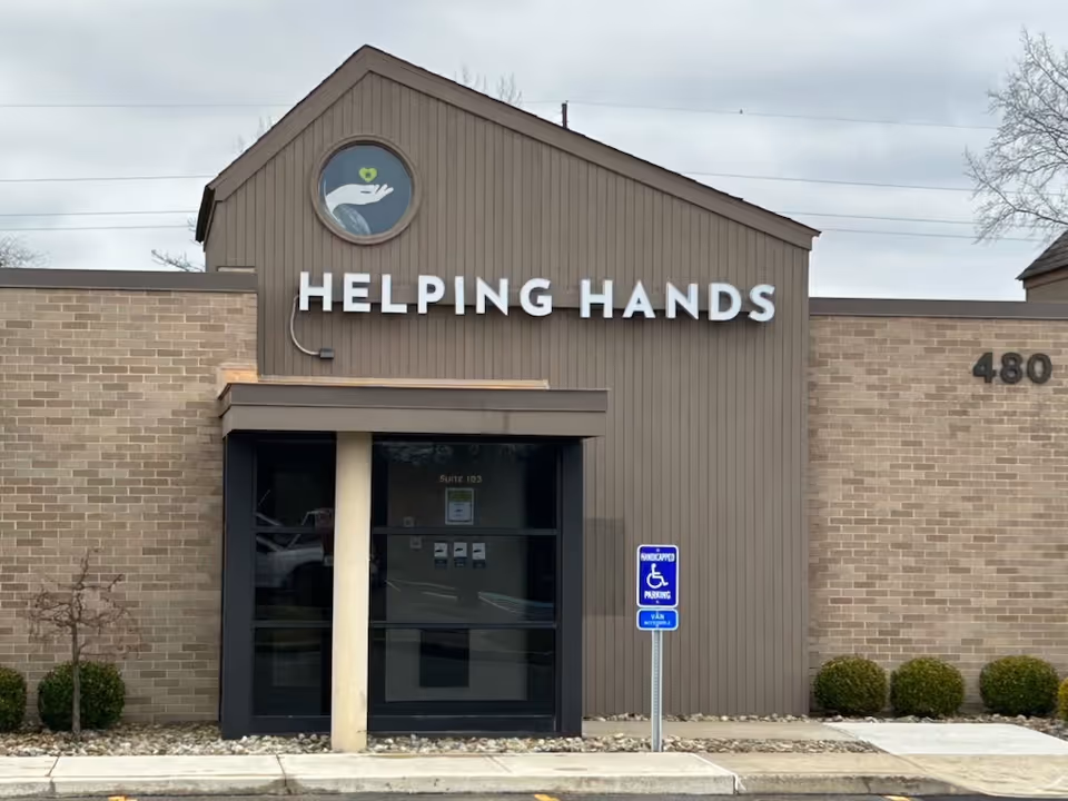 Exterior front of Helping Hands facility with sign and accessible entrance.