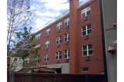 Exterior view of a multi-story red-brick care center with several windows and a fence