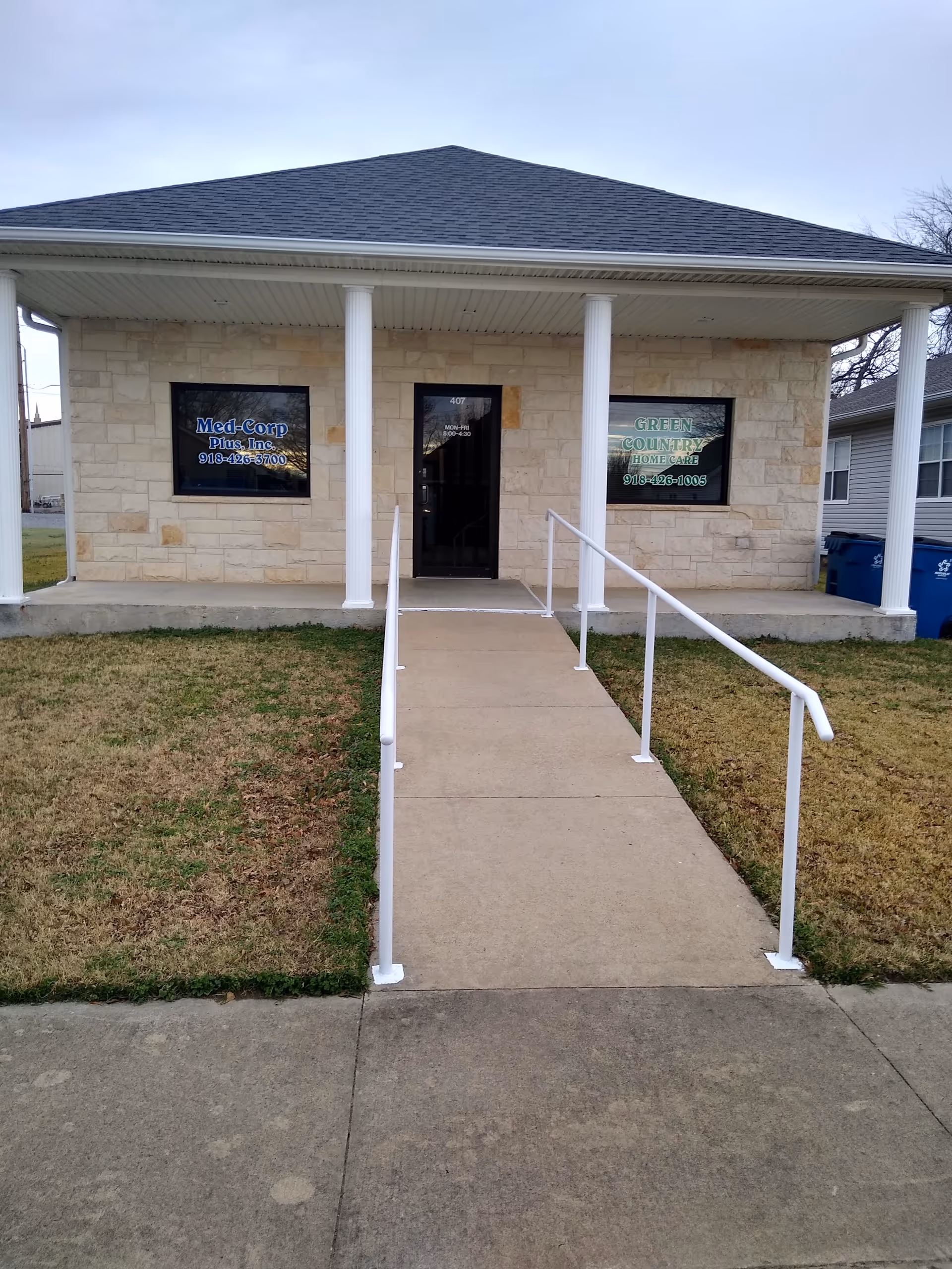 Front exterior of Green Country Home Care with ramp, columns, and stone facade.