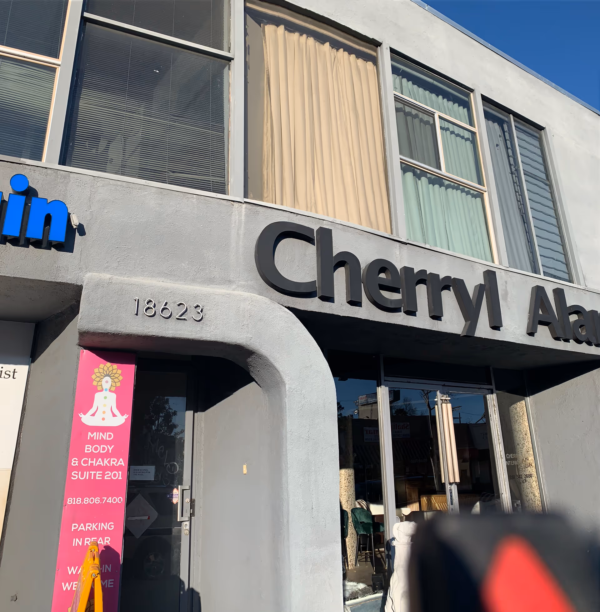 Facade of a storefront with large windows, signage, and a pink wellness banner.