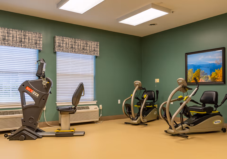 Interior fitness room with exercise bikes and a treadmill against green walls.