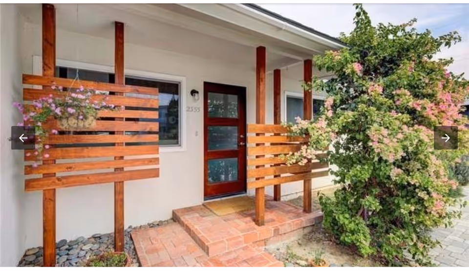 Front entrance of Pepper Tree Assisted Living with wooden railings and flowering plants.