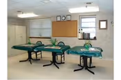 Three teal-covered treatment tables with small plants in a bright nursing home room.