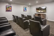 Lounge area with black leather chairs facing a wall-mounted TV.
