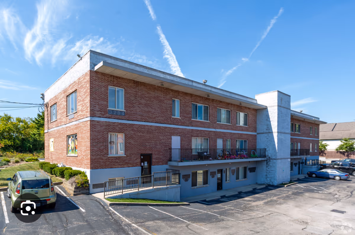 Brick two-story senior care building with front entrance and parking lot.
