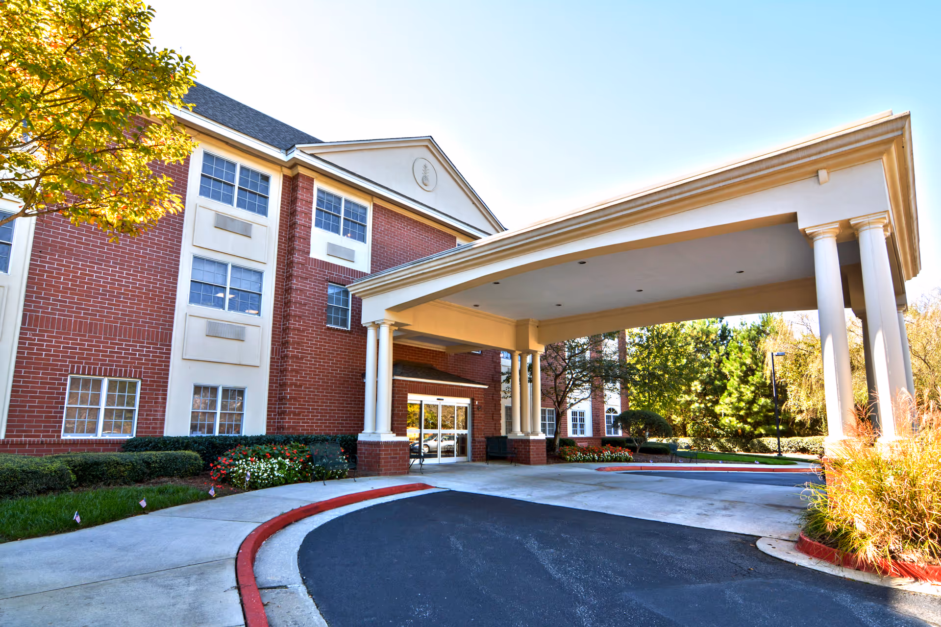 Brick senior living facility exterior with a covered entrance and circular drive.