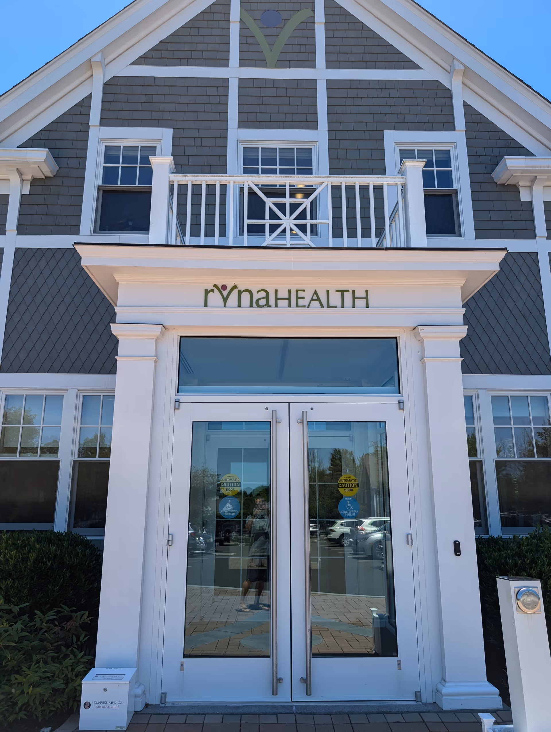 Front view of a RVNAHEALTH building with glass doors and a balcony.