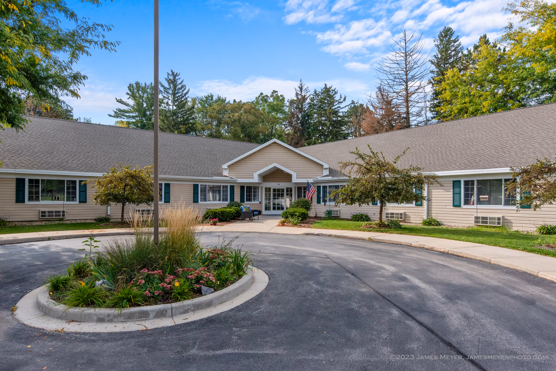 Front of LakeHouse Lake Mills senior living facility with circular driveway and landscaping.