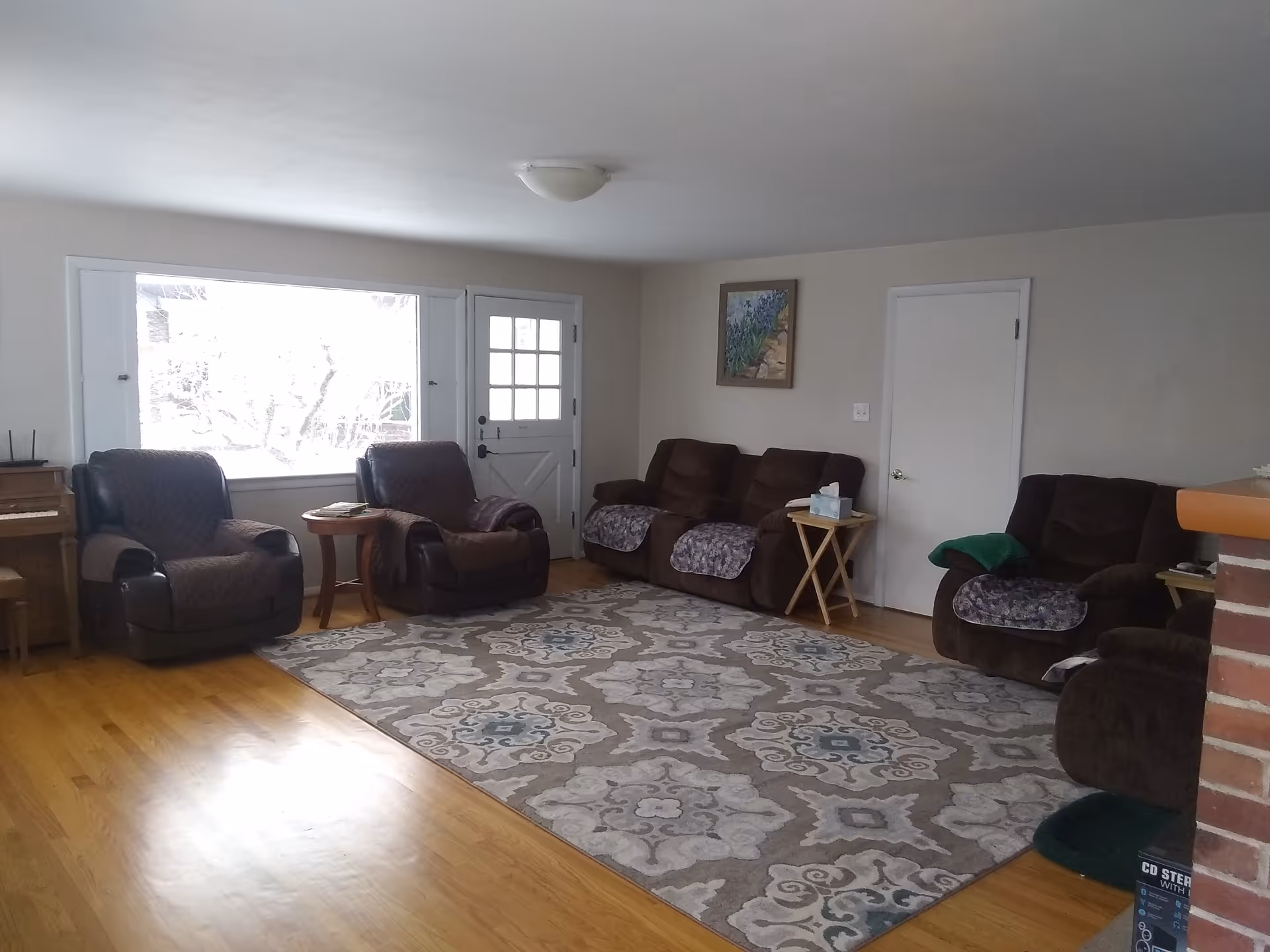 Cozy living room with brown recliners around a patterned rug and wood floor.