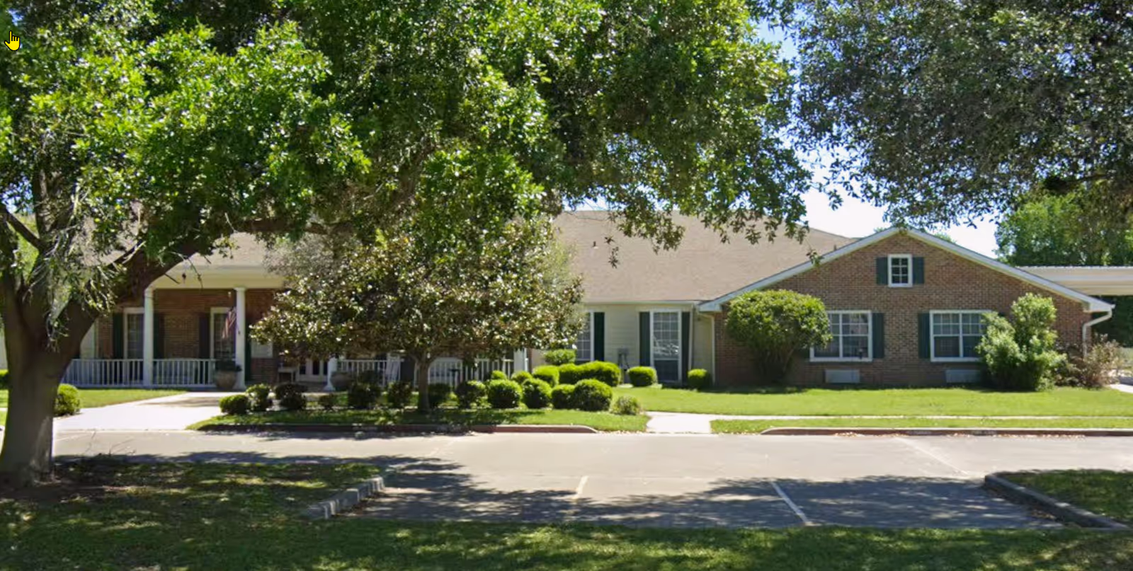 Exterior of Columbus Oaks Assisted Living, a single-story brick building with green lawn and trees.
