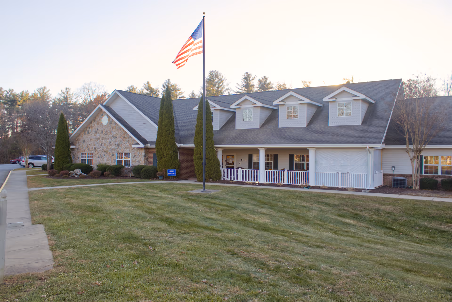 Senior living facility exterior of Fletcher Rehabilitation and Healthcare Center with flagpole, lawn, and porch.