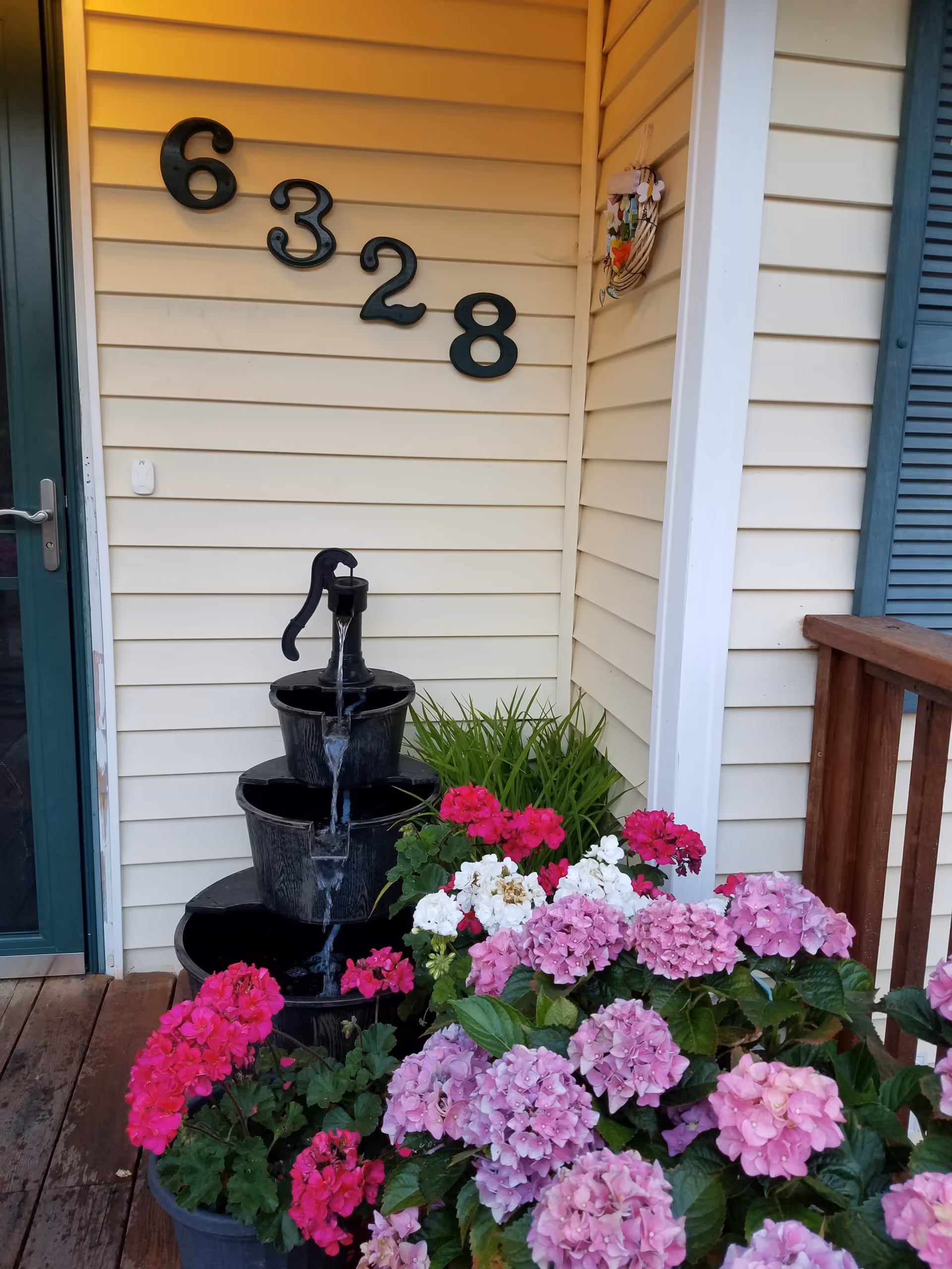 Front porch with tiered fountain and vibrant hydrangeas beside the house number 6328.