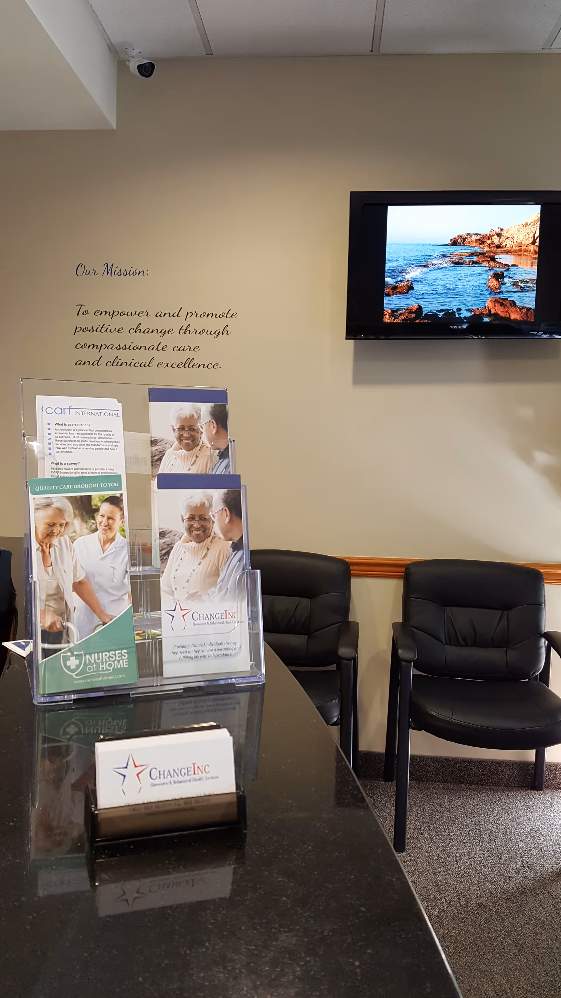 Interior waiting lobby with brochure displays, black chairs, and a wall-mounted mission statement.