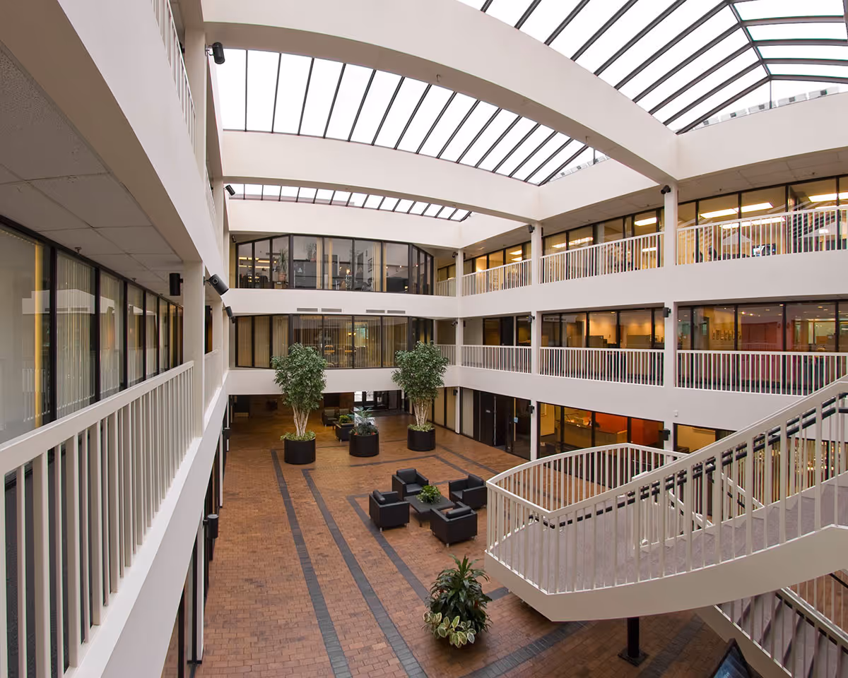 Indoor atrium of a senior care facility featuring a glass skylight, balconies, and seating areas.