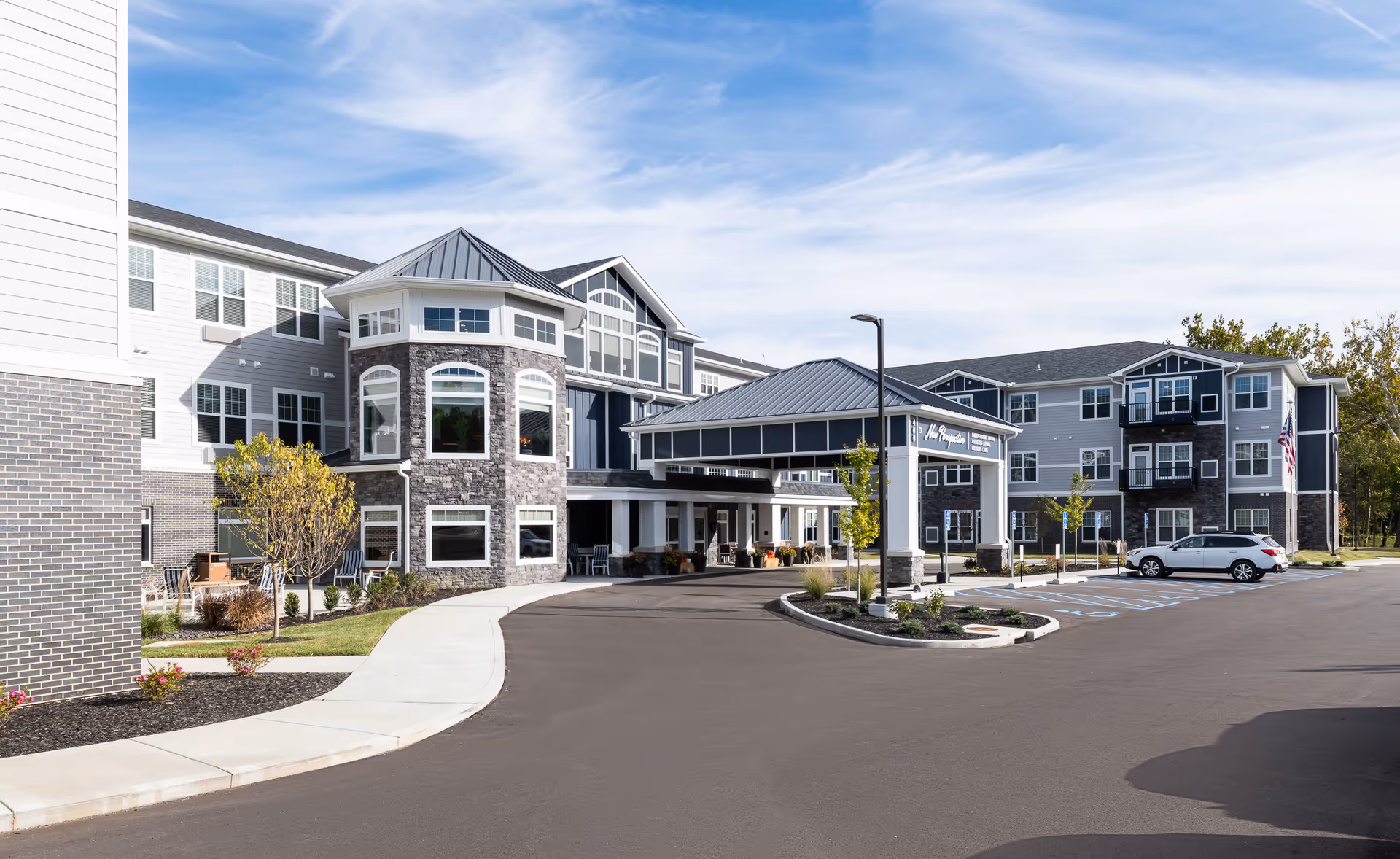 Exterior view of a modern senior living facility with a covered entrance and parking.