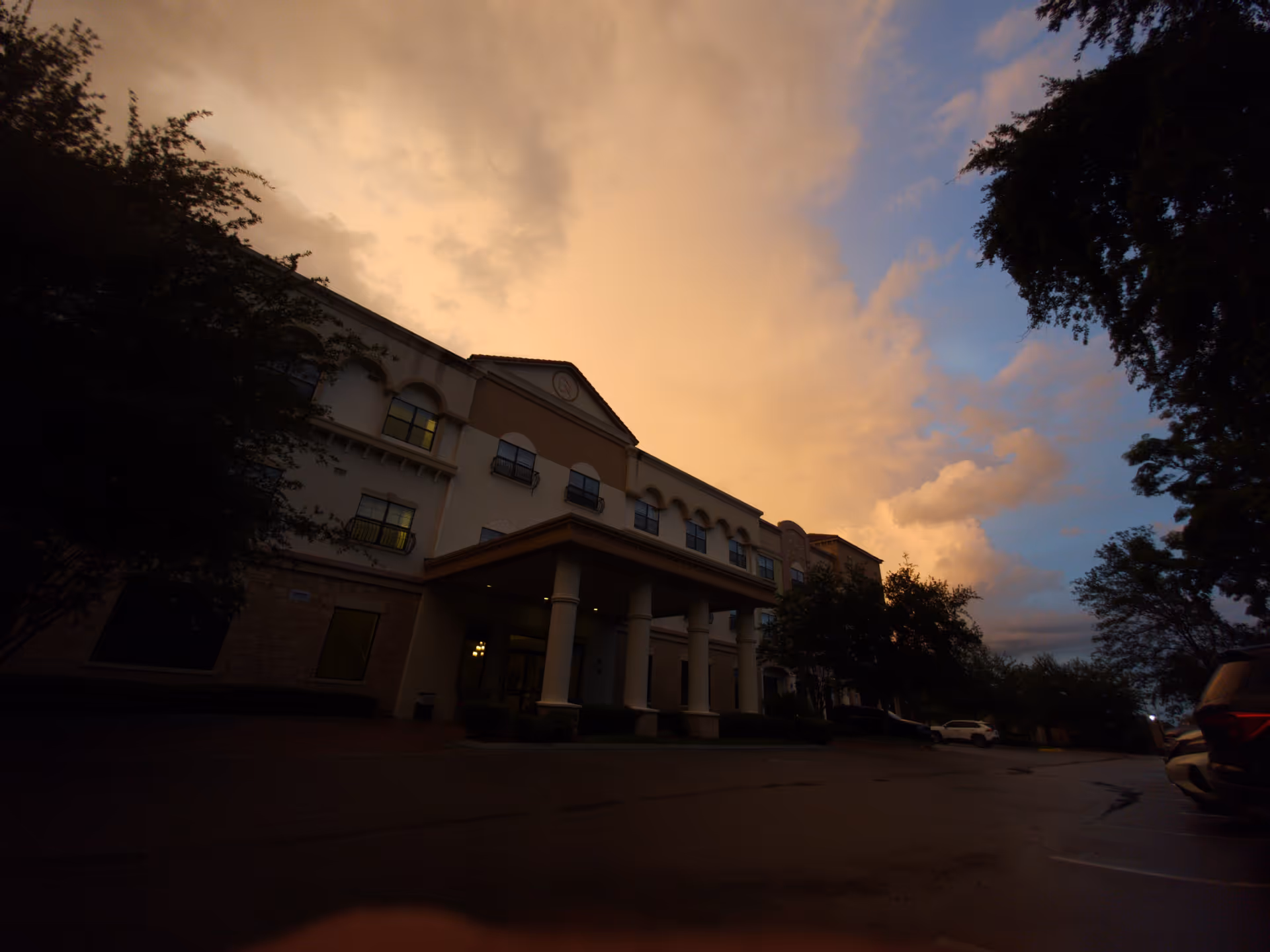 Exterior view of a multi-story senior living building with a covered entrance at sunset.