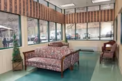 Bright lounge with floral sofas, armchairs, and large windows.