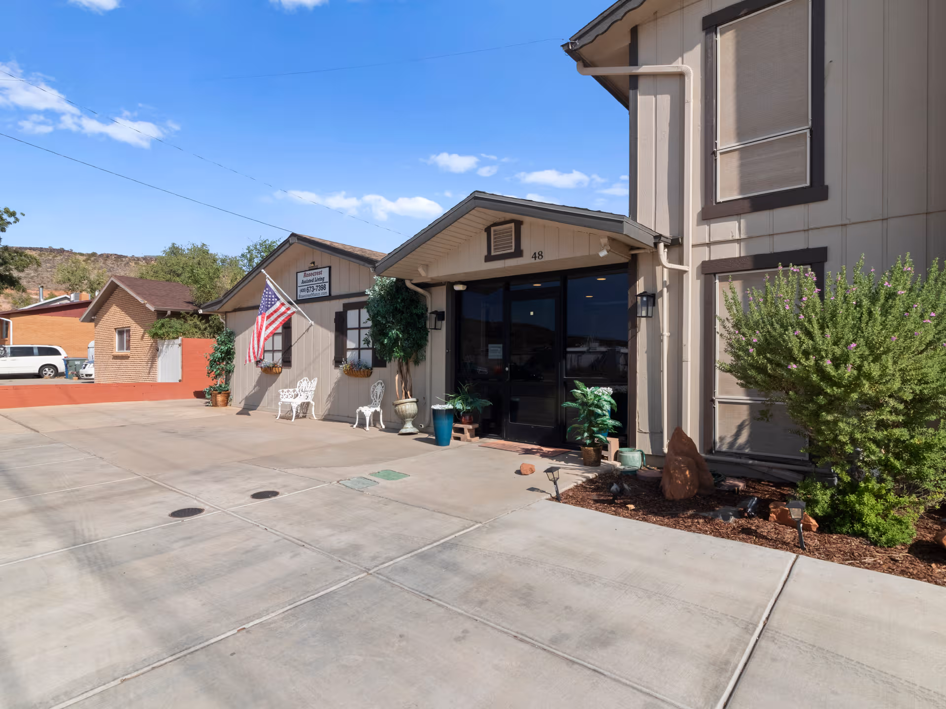 Exterior view of Rosecrest Assisted & Independent Living entrance with chairs and plants.