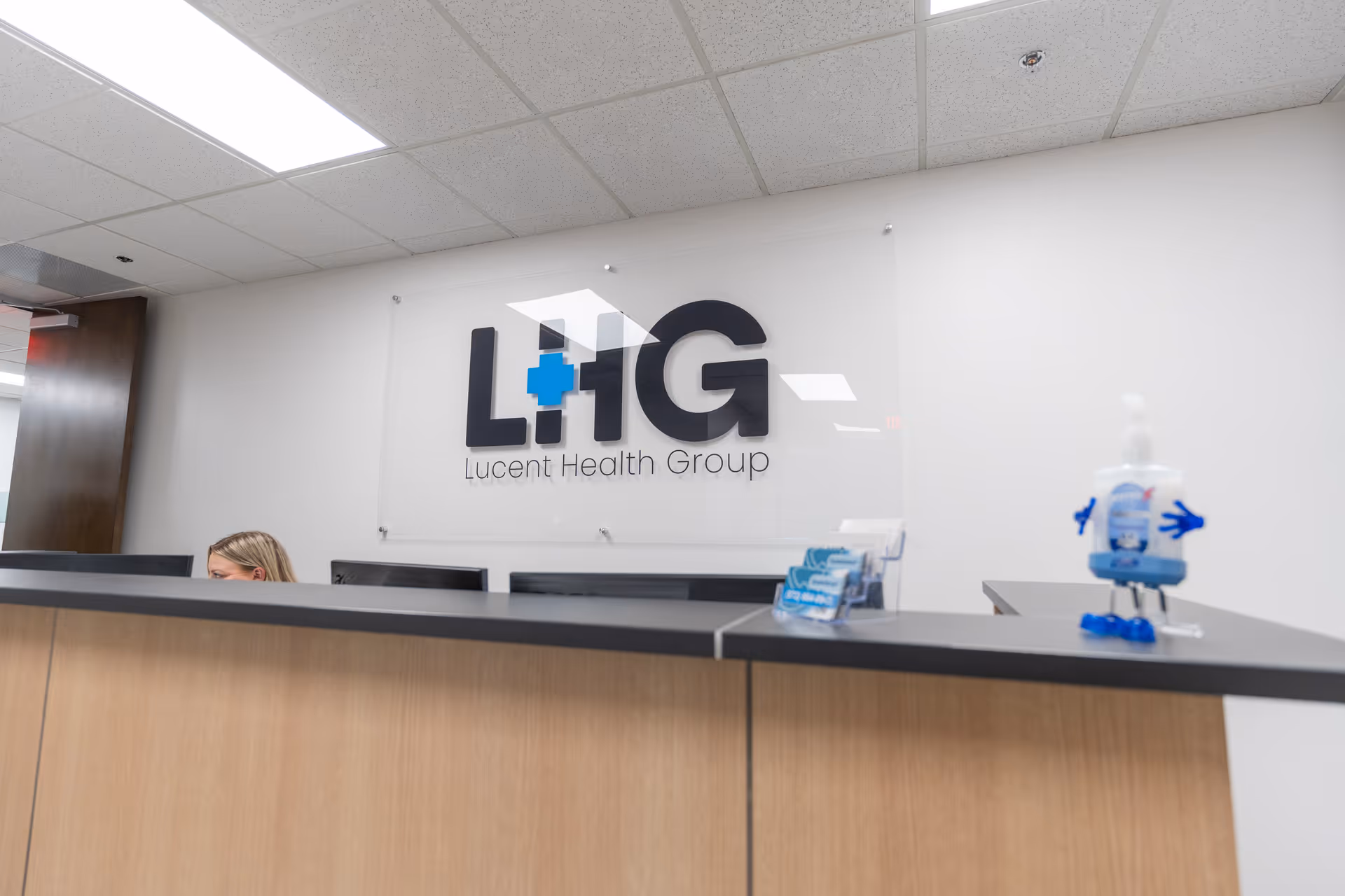 A reception desk in a medical facility with a Lucent Health Group sign on the wall.
