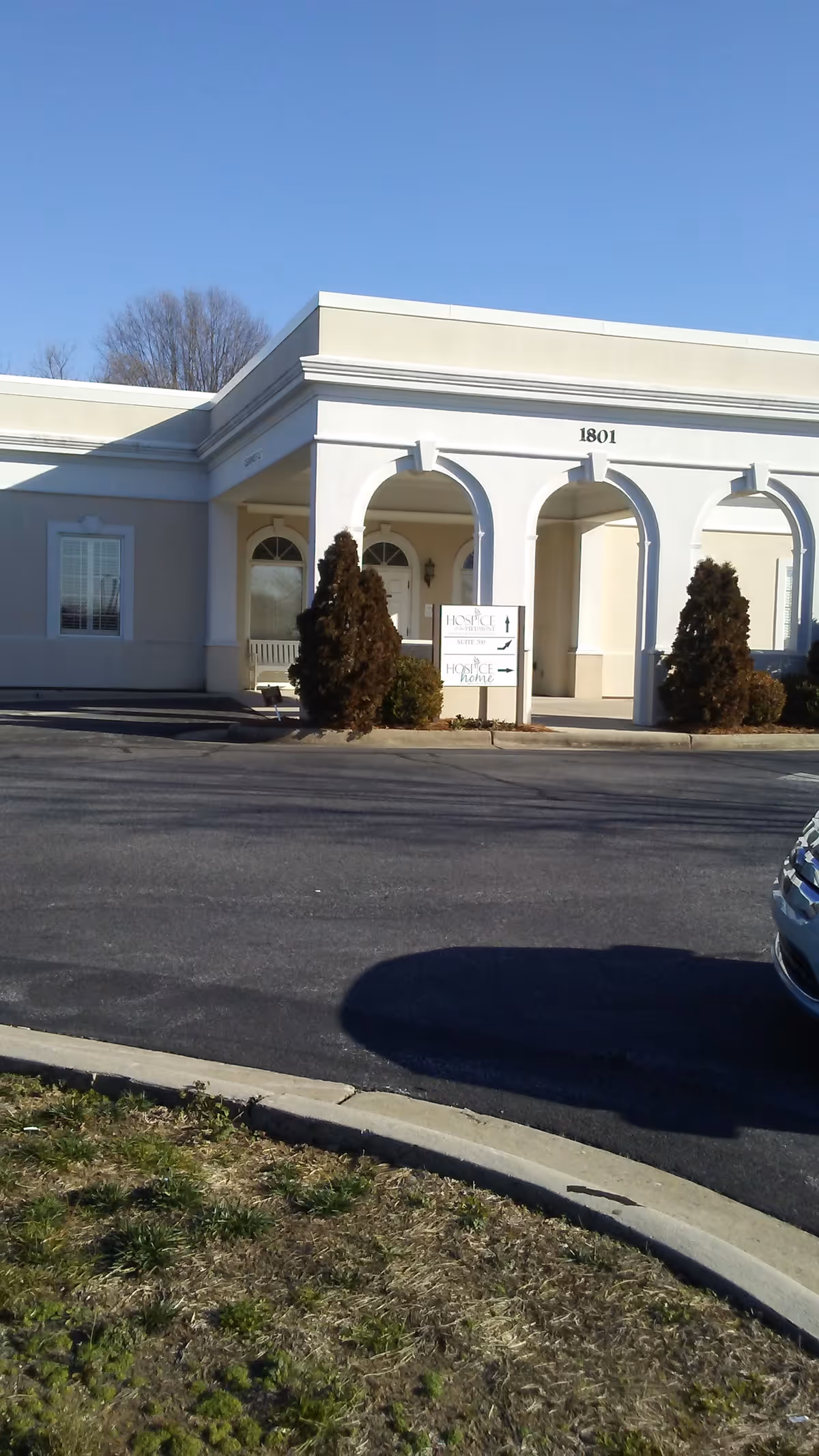 Front view of a pale-colored senior living facility with arches and a driveway.