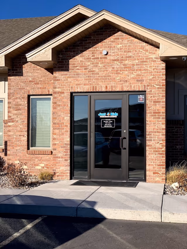 Brick building entrance with a glass door and Just 4 Kids Home Health & Hospice sign.