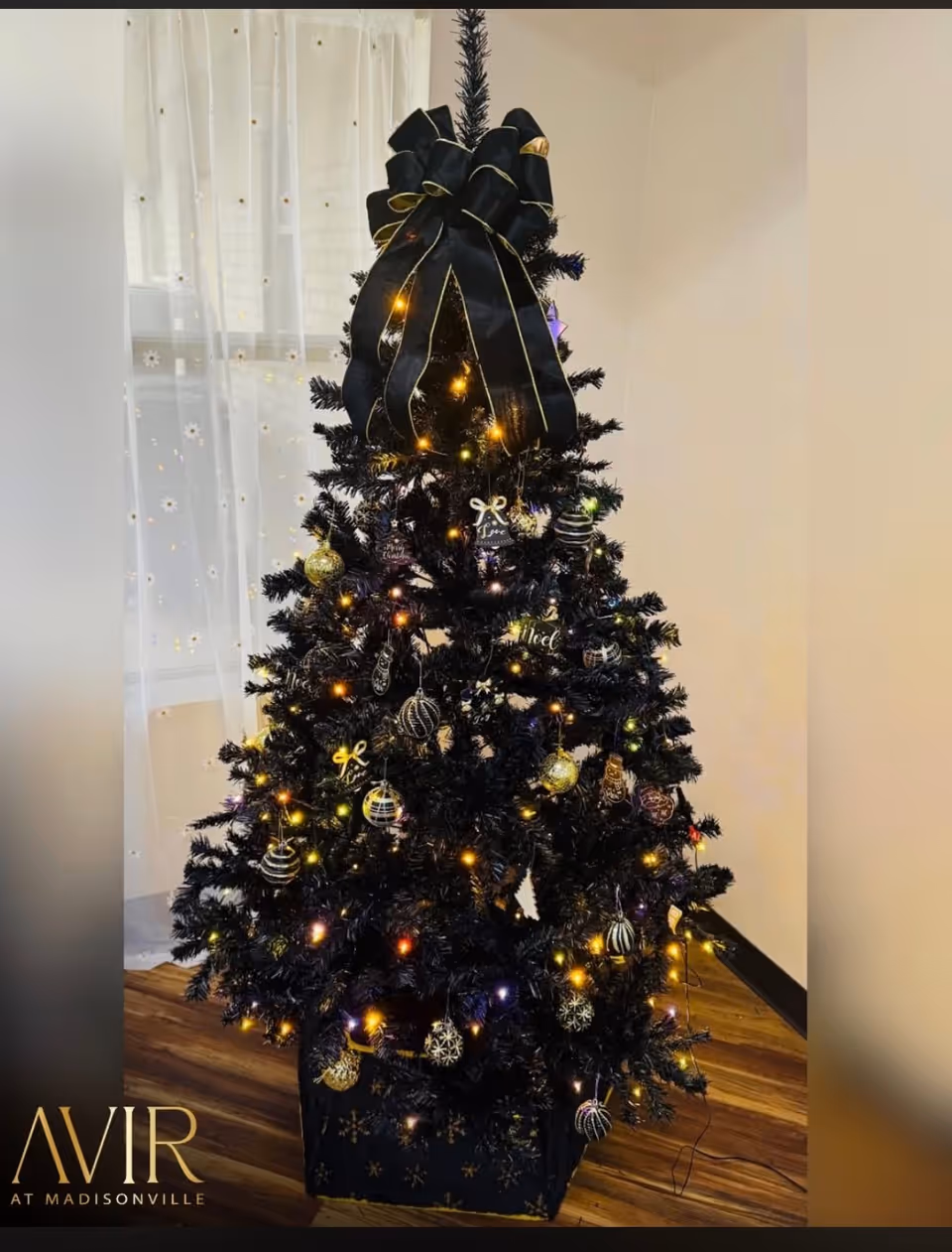 Indoor Christmas tree with black ribbon, lights, and ornaments inside a Riverwood Healthcare room.