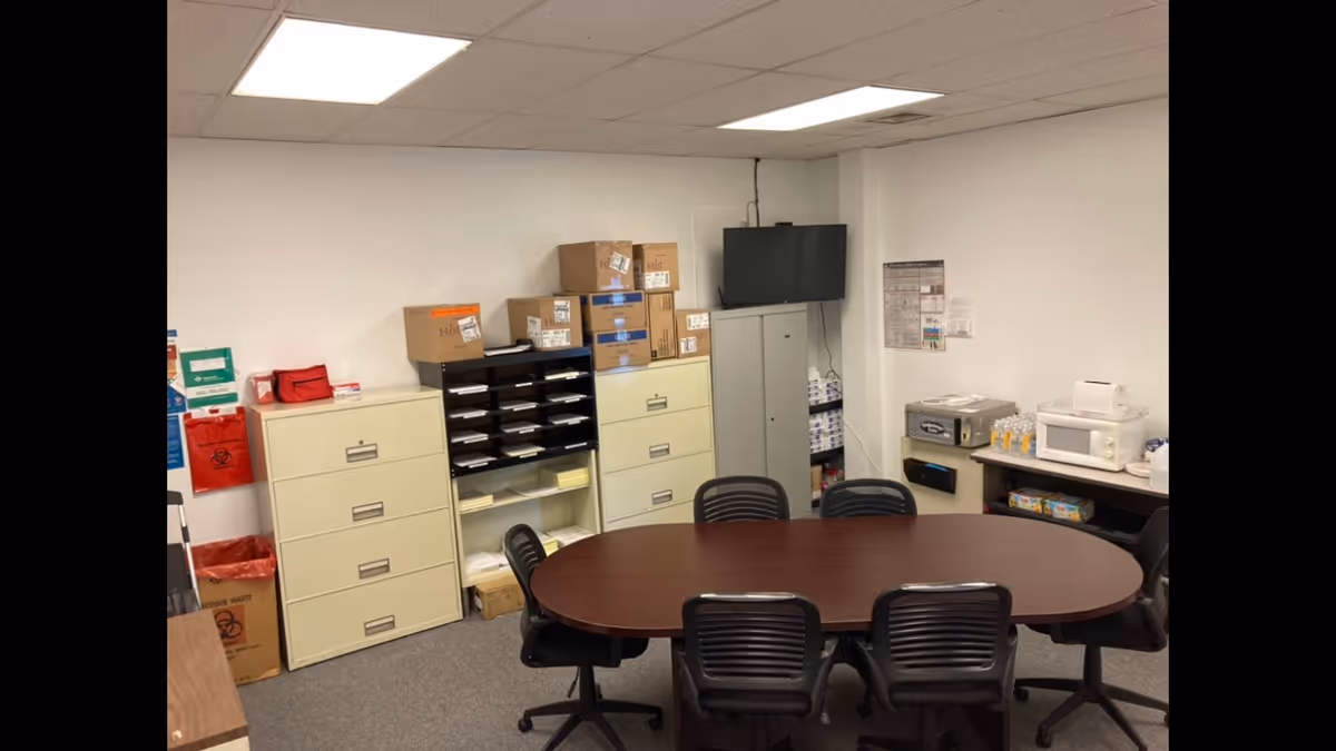 Round wooden table with black chairs in a storage and work area of a facility interior