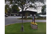 Exterior view of a Quality Life Services facility with a parking lot and trees.