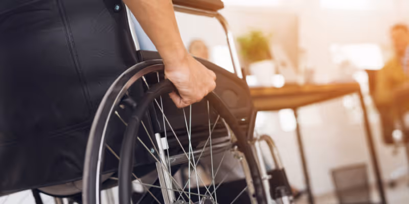 Close-up of a wheelchair being pushed inside a bright senior living facility.