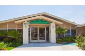 Front entrance of Long Beach Care Center with glass doors and greenery