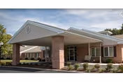 The Elkins Rehabilitation & Care Center building entrance features brick columns and a covered drop-off.