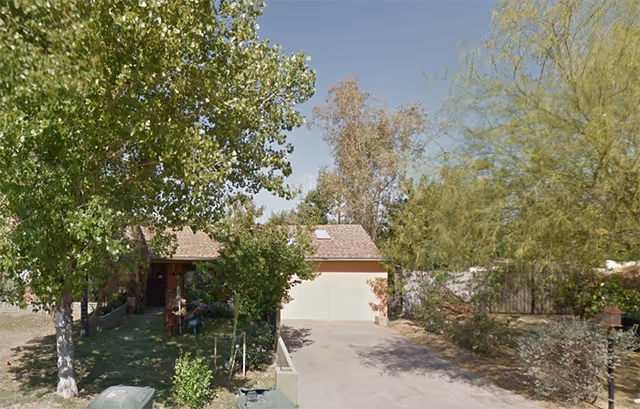 Front exterior view of a single-story Arizona Elderly Care Home with trees and driveway